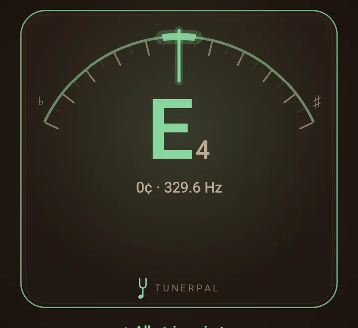 The needle on its faceplate in the Classic theme: an arc of tick marks between a flat and a sharp sign, the needle upright in green over a large green E4 reading 0 cents and 329.6 Hz, the plate's rim green, and the TunerPal mark and wordmark at the foot